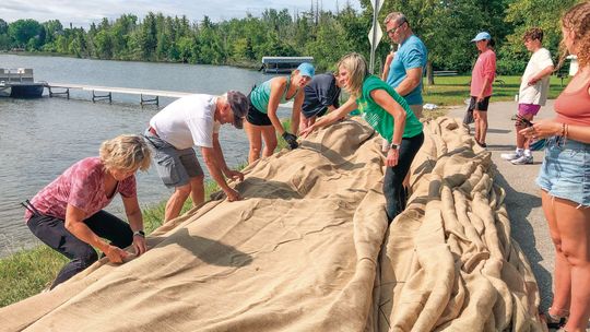 Volunteers turned out with little notice to help prepare rolls of burlap for unrolling onto the bottom of Lake Leelanau in an effort to control the spread of Eurasian water milfoil. Enterprise file photo