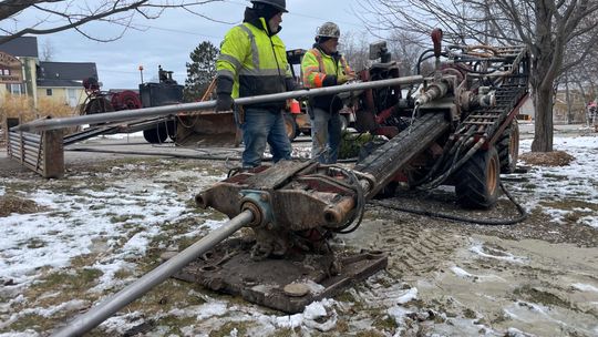 Mike Young and Joe Hess use a trenching machine, which creates a narrow and deep channel for fiber optic cables to be installed under the Lake Leelanau Narrows in March. Enterprise photo by Brian Freiberger