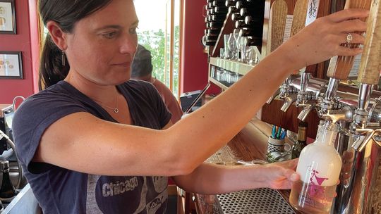 Sarah Hoskins of Tandem Ciders pours a growler full of “Sweet William” pear cider at its Suttons Bay tasting room. Enterprise photo by Brian Freiberger