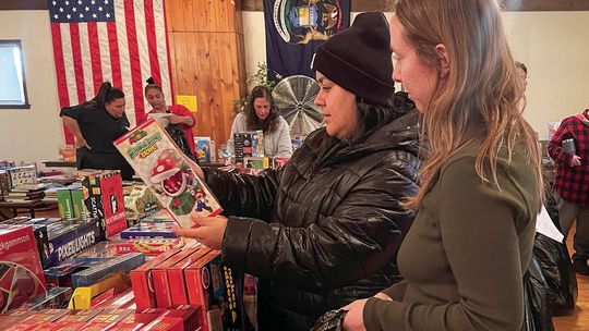 Volunteer Courtney Yaple, right, helps a shopper at the Holiday Needs Program distribution Tuesday at the VFW in Lake Leelanau. Onehundred, fifty-six families — more than 450 people — will have a wonderful Christmas because of the generosity of the community. Enterprise photo by Meakalia P...