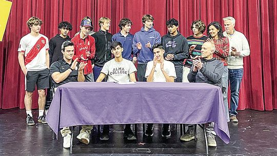 _ Leland senior Agustin Creamer (middle-left) receives a round of applause for his commitment to Alma College last week. Courtesy photo
