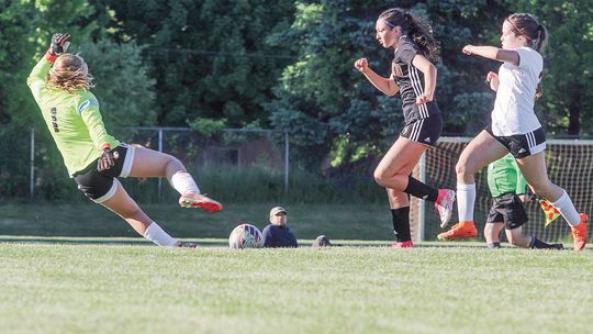 Leland freshman Lillian Connor dashes past a defender to score a goal during a district championship game against Elk Rapids. Enterprise photo by Brian Freiberger