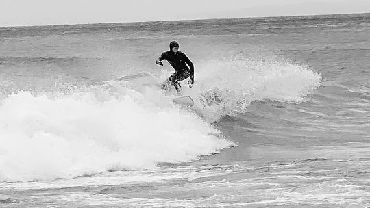A surfer ascended to Northport to catch some waves last week during high winds as local residence enjoy the show. Courtesy photo by Ruth Barry
