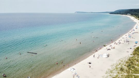 Fun in the sun. Beach-goers take in the summertime weather at Good Harbor Beach in the Sleeping Bear Dunes National Lakeshore. Kids are spotted playing on a floating tree that washed up near shore while other catch some rays and look for treasures along the shore of the beach. Enterprise p...