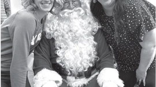 Sisters Whitney Trump, left, and Ashley Brizard used to sit on Santa’s lap at the Omena fire hall when they were growing up. This year, they were there with their parents, Bob and Kori Wheeler, and three generations of the Wheeler family. Photo courtesy of Kori Wheeler