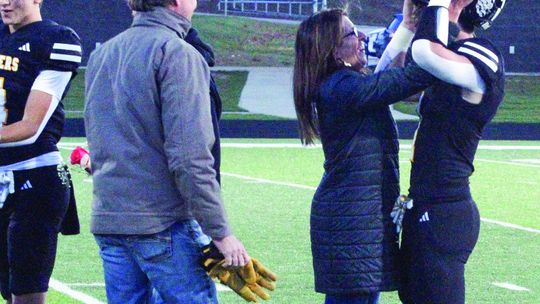 Glen Lake senior Boden Fisher has help getting his helmet on from his mother Cassidy Fisher before taking on Mancelona Friday during senior night. Enterprise photo by Brian Freiberger