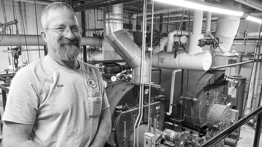 Bob Bufka stands in front of the aging boilers which have provided heat for Glen Lake School for 50 years. Enterprise photo by Brian Freiberger