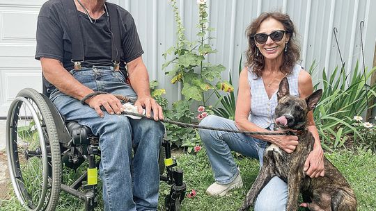 Gary Lowe (left) and Linda Gottwald (right) play with Hawthorne at the Great Lakes Humane Society near M-72. Enterprise photo by Brian Freiberger