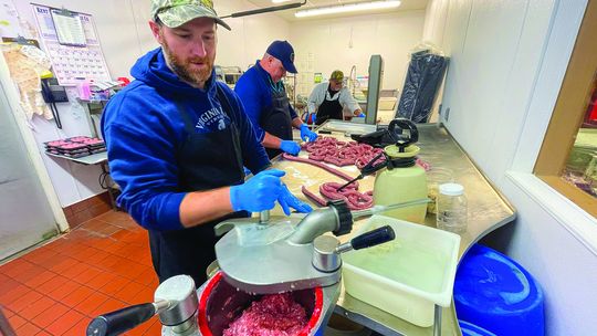 Roger Mikowski (left), Donald Jackson (middle), and Lennie Mikowski (right) of Mikowski’s Meat &amp; Deli cut up fresh meat for purchase at Hansen Foods in Suttons Bay every Thursday. The two local companies announced a partnership with a community cookout planned for August 16 from noon t...