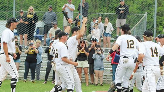 Glen Lake seniors accept the program’s 12th consecutive district championship and walk it over to celebrate with the rest of the Lakers after defeating Suttons Bay 12-0. Enterprise photo by Brian Freiberger