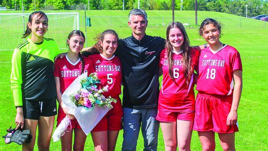 Suttons Bay soccer seniors stand with coach Randy U’Ren during senior night last week. From left to right: Keeley TwoCrow, Lauren Lint, Elena Grant (St. Mary), U’Ren, and St. Mary players Sarah Bunek, and Amanda Tarsa.