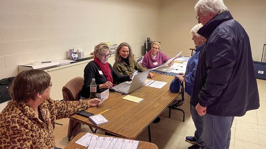 Election workers stationed at Suttons Bay Public School are pictured helping people check in before they get their ballots on Tuesday evening. Enterprise photo by Meakalia Previch-Liu