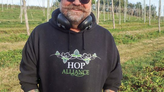 Hop Alliance owner Brian Tennis stand in his Omena Hop Yard earlier this month. Enterprise photo by Brian Freiberger