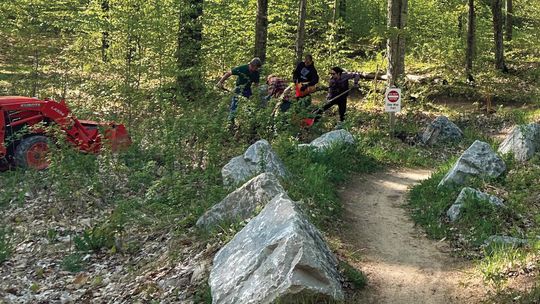 Members and volunteers of the Leelanau Conservancy are seen hard at work, maintaining the mountain bike trails at Palmer Woods Forest Reserve Tuesday night. Enterprise photo by Everett Howell