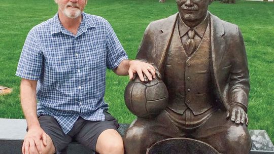 Muldowney sits with a James Naismith statue in Lawrence, Kansas to celebrate his love for basketball. Courtesy photo