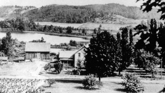 This c. 1925 photo taken from the hillside across the road is clearly earlier than the one in last month’s article. Note the covered front porch and the traditional house detailing. All of the original frame houses of Port Oneida (which generally followed earlier log cabins) seem to have h...