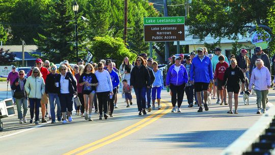 Nearly a hundred bridge walkers descended across the narrows bridge of Lake Leelanau to celebrate Labor Day. The walkers started at Pedaling Beans before walking across the bridge to Boathouse Vineyards for an exhilarating duck race on Monday. Enterprise photo by Brian Freiberger