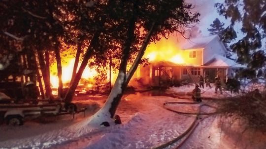 Firefighters battle a blaze on the 1000 block of Sunset Shores Drive in Lake Leelanau Monday morning, right. Below, area fire departments faced plenty of obstacles including snowy conditions that led to three fire apparatus to become stuck. Courtesy photo