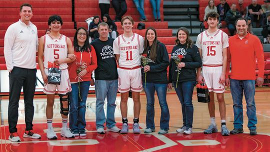 Suttons Bay boys basketball seniors Dennis Anderson, Lucas Gordan, and Tyler Porter stand with their parents on senior night. Photo courtesy of Trudy Galla