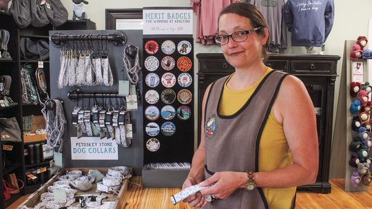 Meg Paxton shows off her original Petoskey Stone Dog Collars at The Blue Maple Corner in Maple City. Enterprise photo by Brian Freiberger
