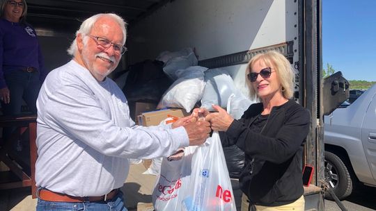 Nanette Walter of Suttons Bay Township dropped off bags of goods for Leelanau Christian Neighbors while attending service at West Side Community Church. Accepting the donation at the LCN panel truck is board member Steve Stanton. Enterprise photo by Alan Campbell