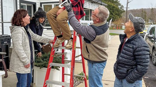 Decking the halls in the village of Omena are, from left, Kerri Magrini, Susan Krusel, William Krusel (on ladder), Bill Krusel and Bob Nakamura. Courtesy photo