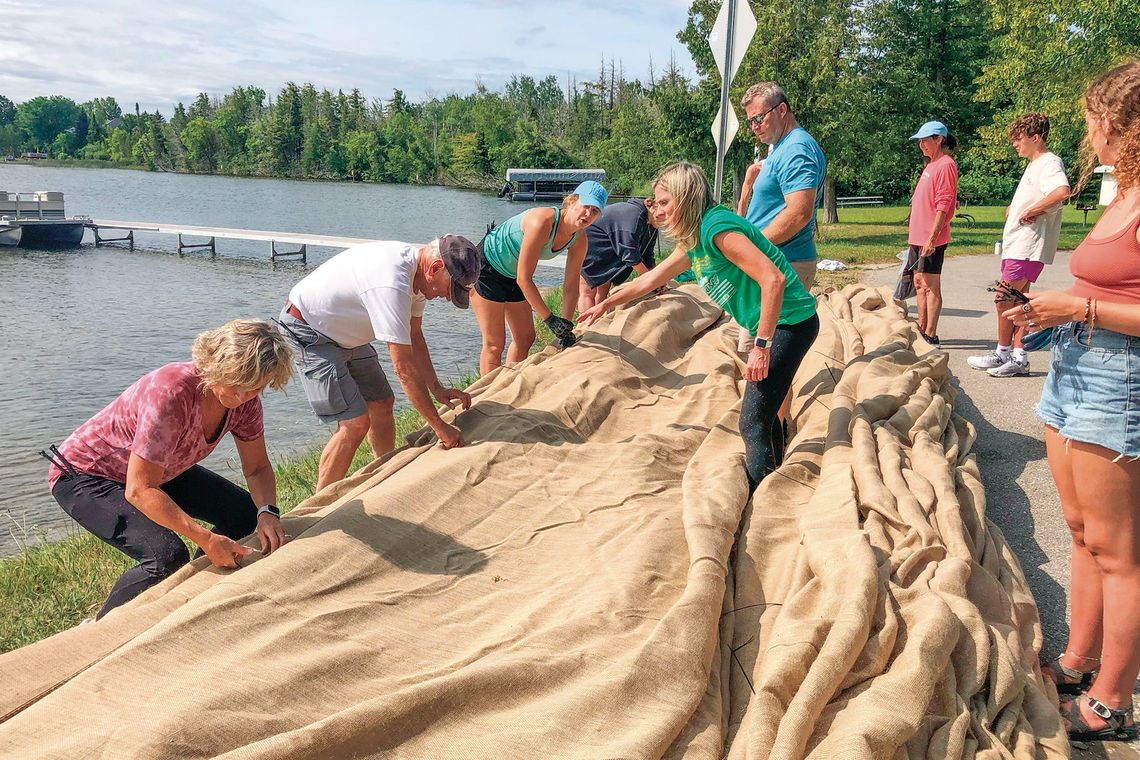 Volunteers turned out with little notice to help prepare rolls of burlap for unrolling onto the bottom of Lake Leelanau in an effort to control the spread of Eurasian water milfoil. Enterprise file photo