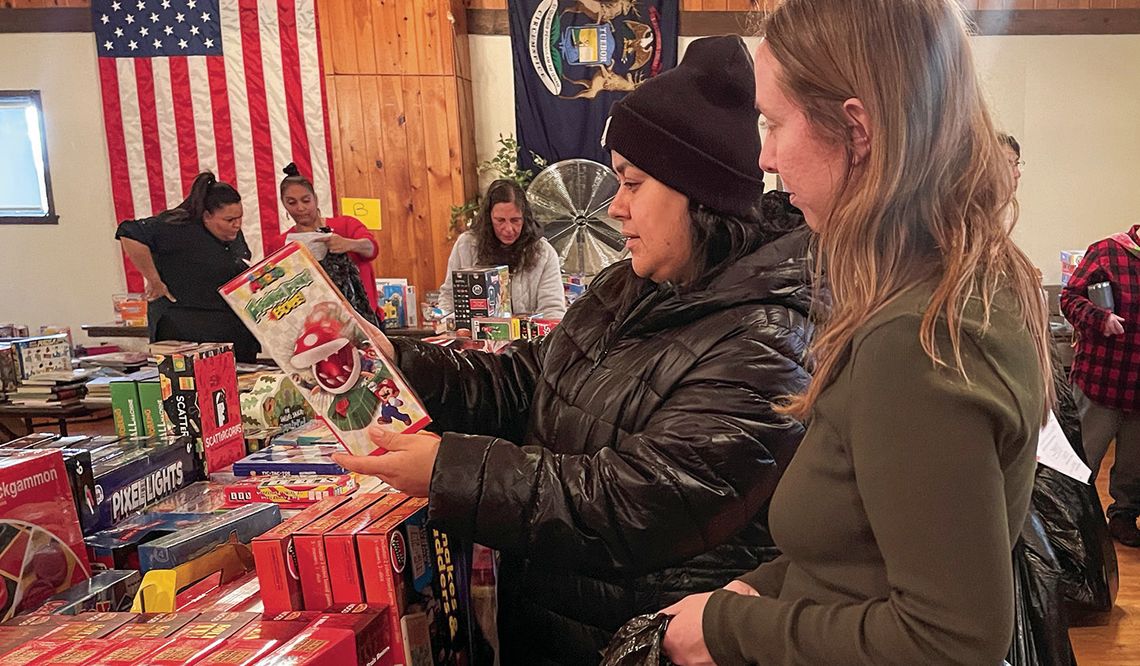 Volunteer Courtney Yaple, right, helps a shopper at the Holiday Needs Program distribution Tuesday at the VFW in Lake Leelanau. Onehundred, fifty-six families — more than 450 people — will have a wonderful Christmas because of the generosity of the community. Enterprise photo by Meakalia P...