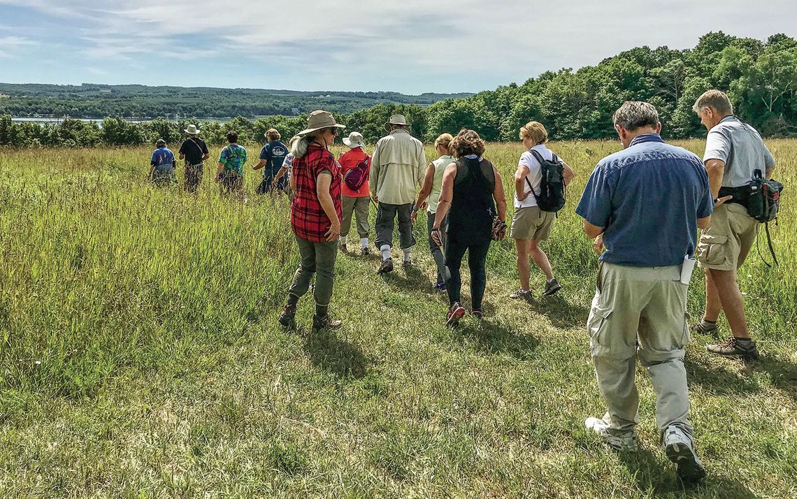 A group of hikers walk through a grassy field in the Clay Cliffs Natural Area near Leland. Clay Cliffs is one of the Leelanau Conservancy’s “must-see” trails, according to conservancy Communications Specialist Brighid Driscoll. Courtesy photo.
