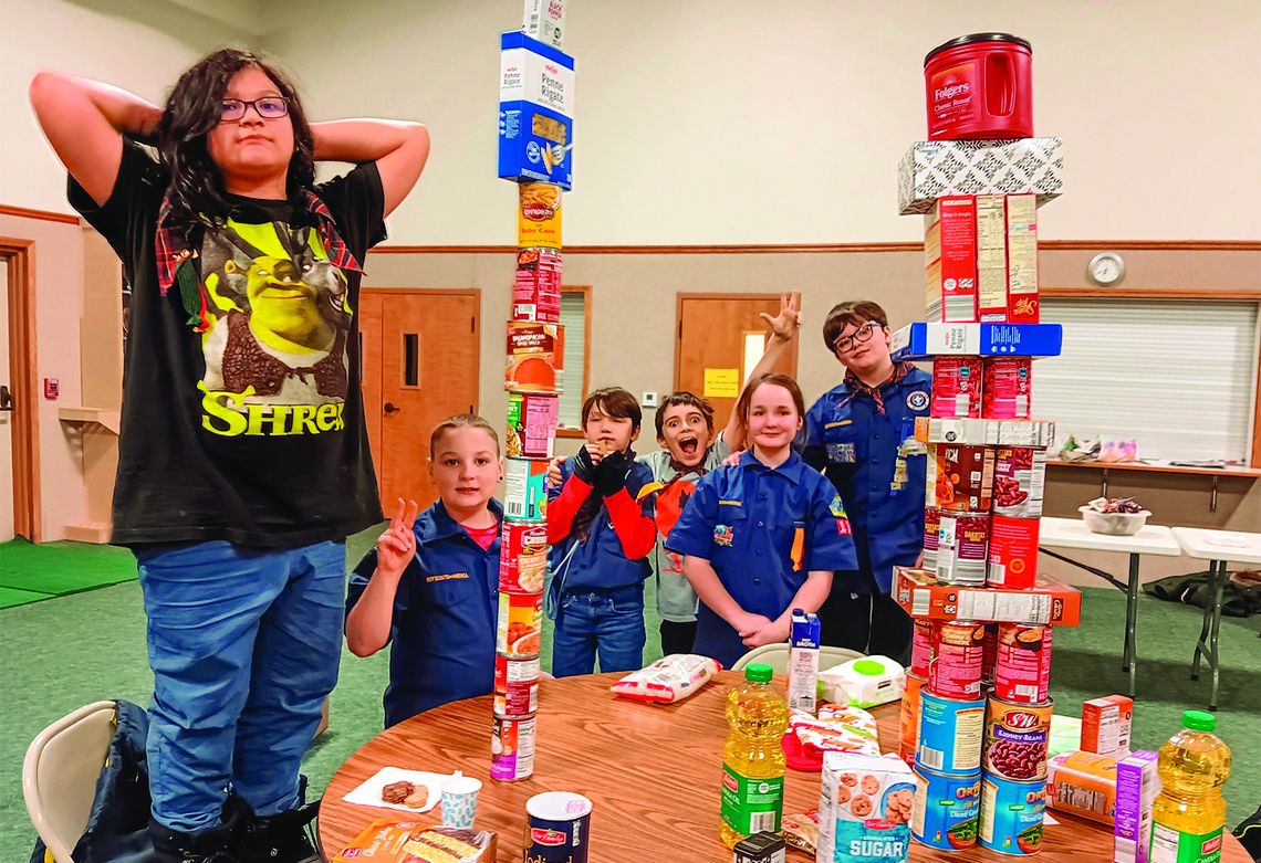 The Webelos Den of Pack 131 with the two stacks of food they collected for the Leelanau Christian Neighbors Food Pantry. One stack measured 46 inches high, the other stack measured 38 inches high.Webelos Scouts who participated were Wamigo Winchester in front and from left Beau Underhill,...