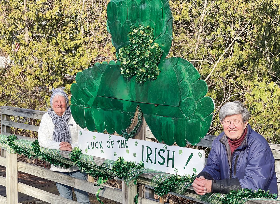 Judy Walter (left) and her husband, Jon, have been decorating the bridge off Elm Street in Suttons Bay since last July. Their latest creation, a giant green shamrock for St. Patrick’s Day, is on display for those passing by to see. Enterprise photo by Meakalia Previch-Liu