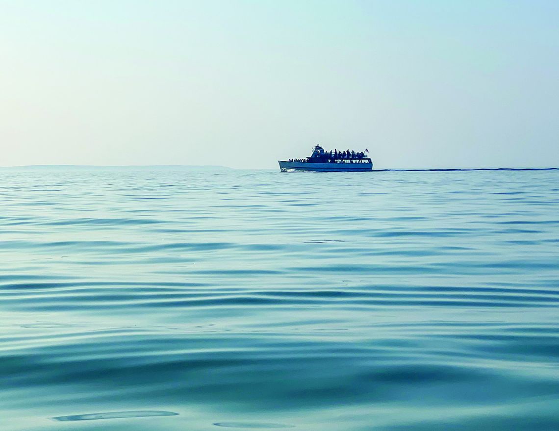 Beach-goers at Good Harbor Bay spotted the Mishe-Mokwa cruising the smooth waters during a sunset cruise on Sunday. Enterprise photo by Brian Freiberger
