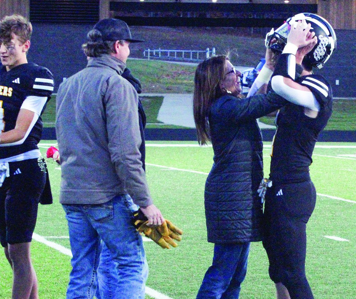 Glen Lake senior Boden Fisher has help getting his helmet on from his mother Cassidy Fisher before taking on Mancelona Friday during senior night. Enterprise photo by Brian Freiberger