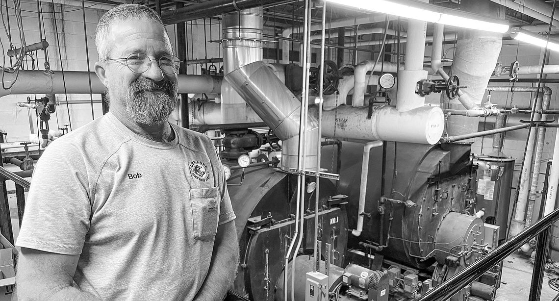 Bob Bufka stands in front of the aging boilers which have provided heat for Glen Lake School for 50 years. Enterprise photo by Brian Freiberger