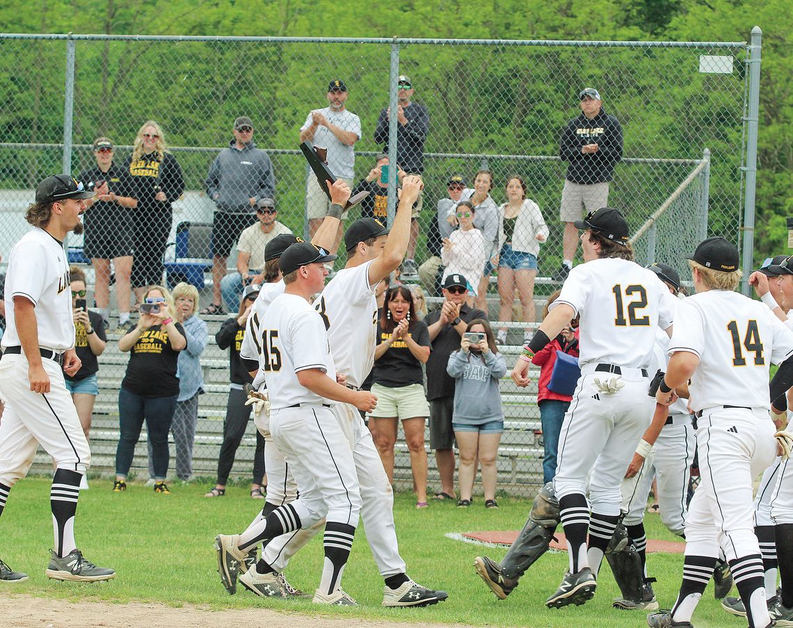 Glen Lake seniors accept the program’s 12th consecutive district championship and walk it over to celebrate with the rest of the Lakers after defeating Suttons Bay 12-0. Enterprise photo by Brian Freiberger