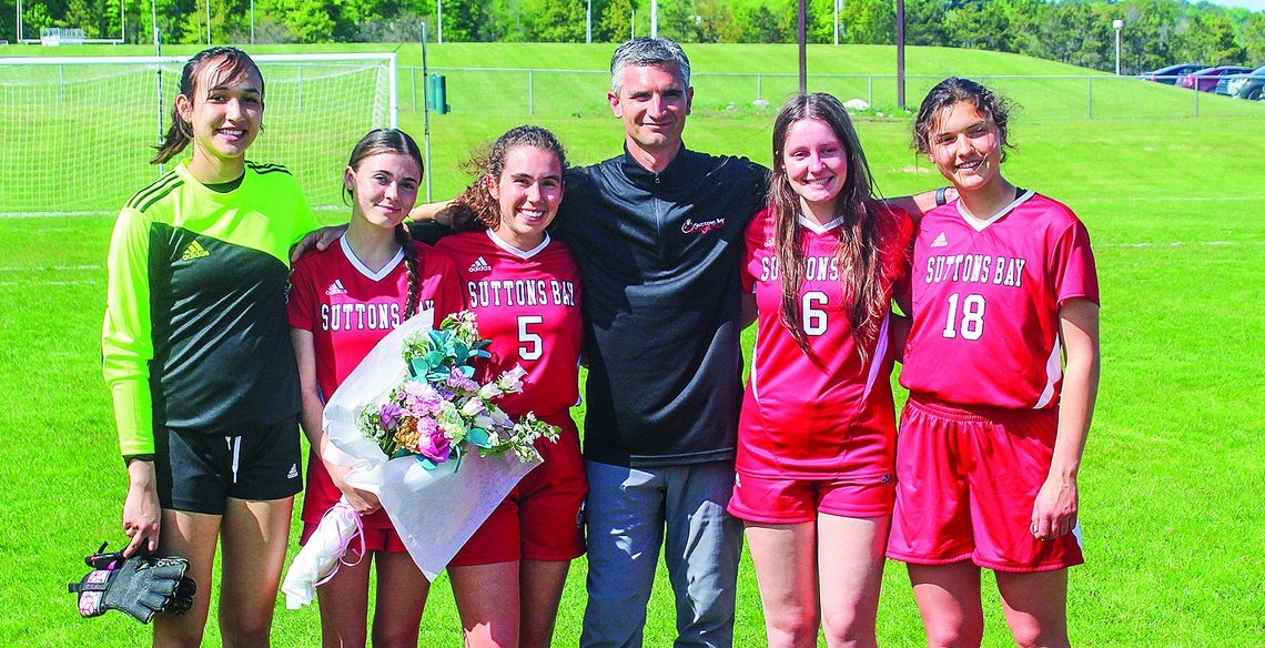 Suttons Bay soccer seniors stand with coach Randy U’Ren during senior night last week. From left to right: Keeley TwoCrow, Lauren Lint, Elena Grant (St. Mary), U’Ren, and St. Mary players Sarah Bunek, and Amanda Tarsa.