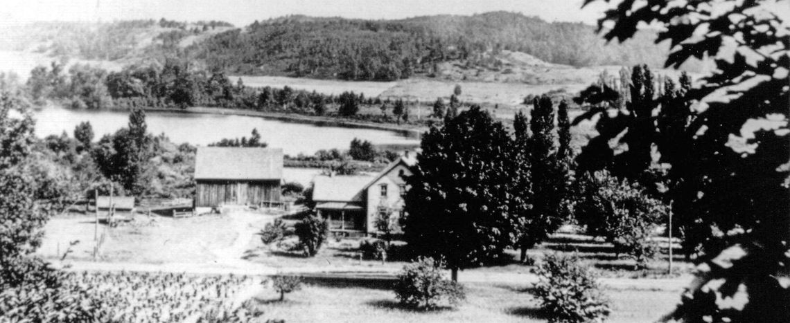 This c. 1925 photo taken from the hillside across the road is clearly earlier than the one in last month’s article. Note the covered front porch and the traditional house detailing. All of the original frame houses of Port Oneida (which generally followed earlier log cabins) seem to have h...