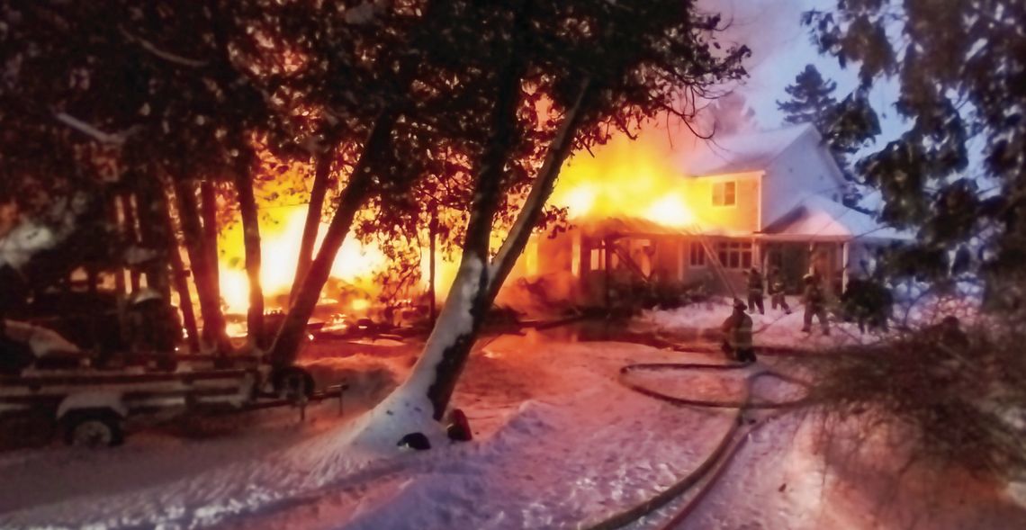 Firefighters battle a blaze on the 1000 block of Sunset Shores Drive in Lake Leelanau Monday morning, right. Below, area fire departments faced plenty of obstacles including snowy conditions that led to three fire apparatus to become stuck. Courtesy photo