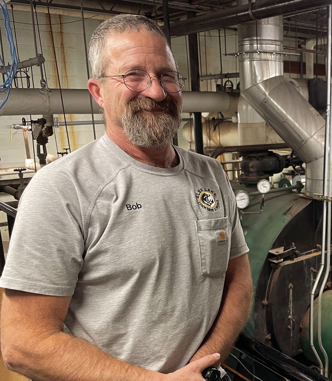 Bob Bufka stands in front of the aging boilers which have provided heat for Glen Lake School for 50 years in January. Enterprise photo by Brian Freiberger