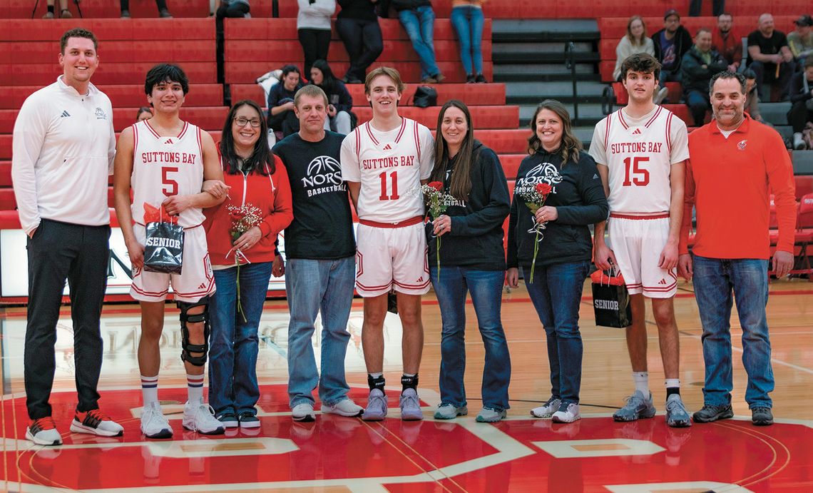 Suttons Bay boys basketball seniors Dennis Anderson, Lucas Gordan, and Tyler Porter stand with their parents on senior night. Photo courtesy of Trudy Galla