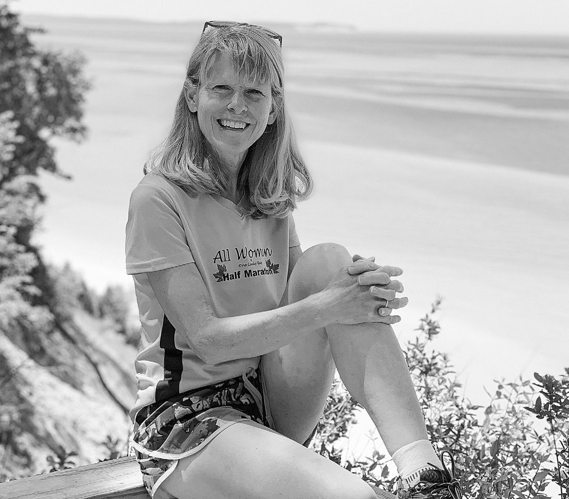 Kelly Slater of Suttons Bay, vice president of the Traverse City Track Club, poses in front of the waters of Lake Michigan. Courtesy photo