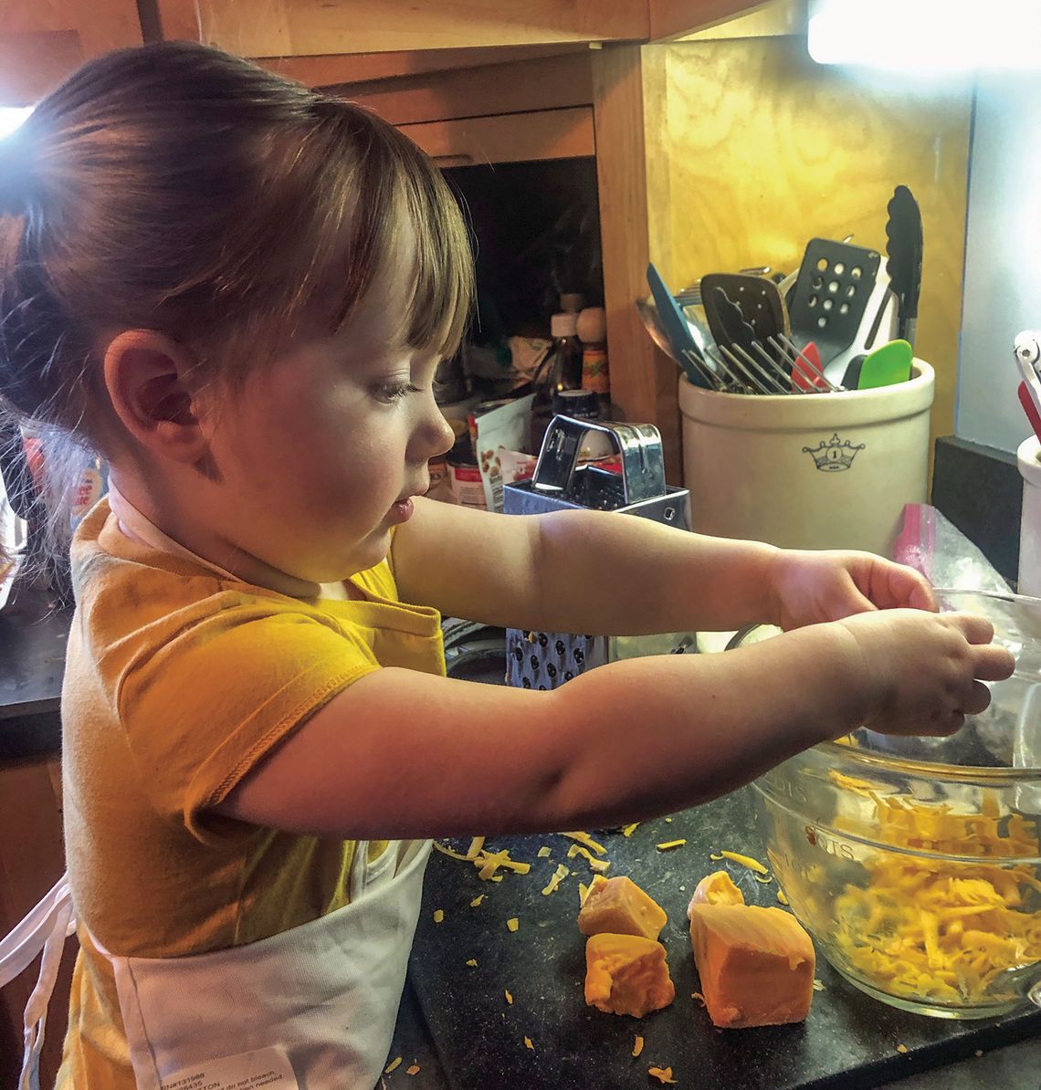 This wee one helps out her grandmother in the kitchen breaking up cheese for macaroni and cheese This wee one helps out her grandmother in the kitchen breaking up cheese for macaroni and cheese