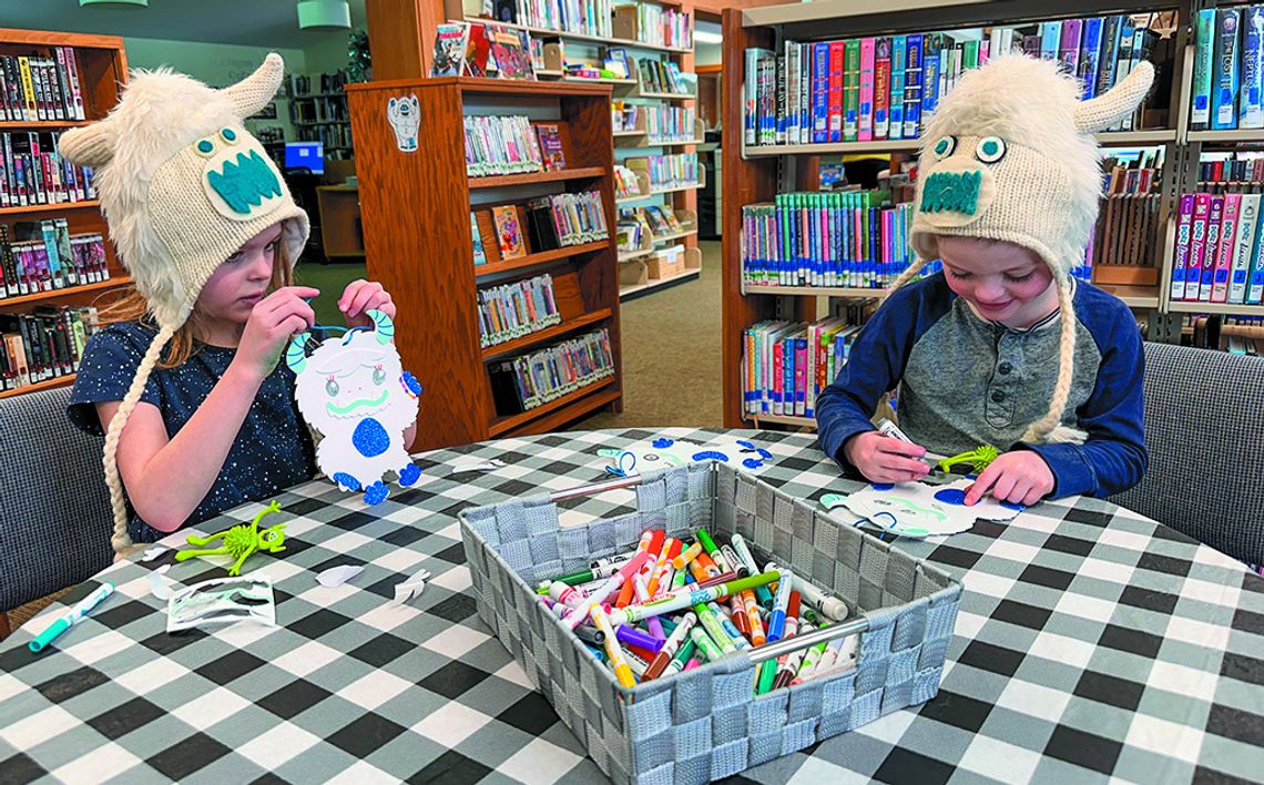 Two siblings wearing yeti hats that their grandparents got them while enjoying the activities at the Suttons Bay-Bingham Township library. Enterprise photo by Amy Hubbell
